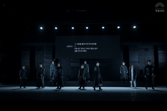 공연 실황사진. 11명의 배우, 2명의 수어통역사, 1명의 연주가 모두가 무대 위에 위치합니다. 모두 검은색 의상을 입었습니다.